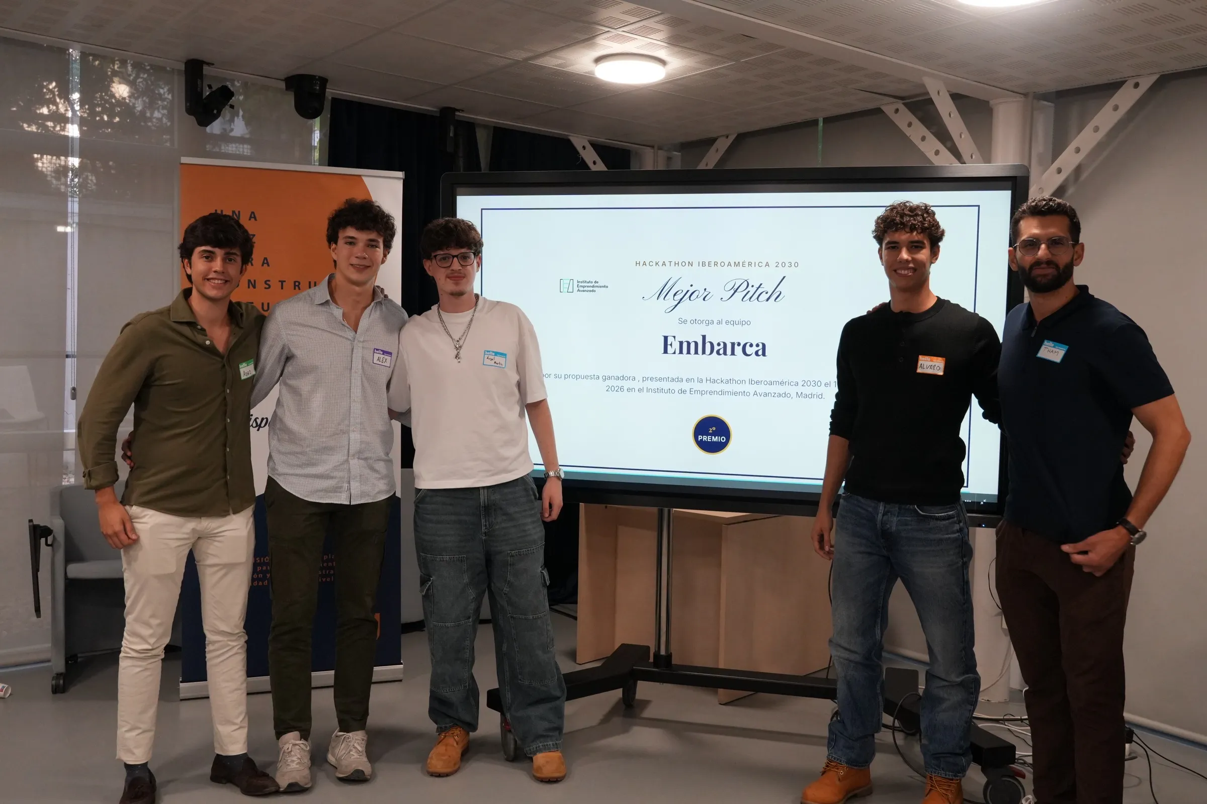The team, all five, standing by the screen that names Embarca best pitch